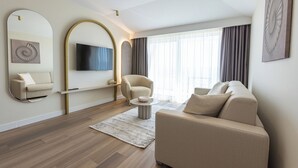 Una sala moderna con un sofá, un sillón y un televisor de pantalla plana montado en la pared.