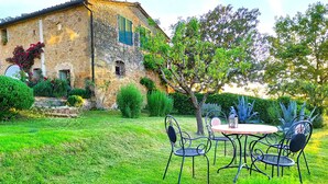 Un edificio de piedra con jardín y zona de estar al aire libre.