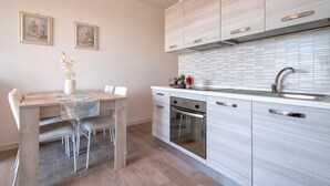A modern kitchen with a dining table, chairs, a built-in oven, and a sink. - Sardinia Re - Smeralda 16 (Castelsardo)