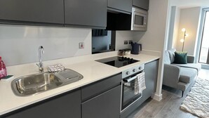 A modern kitchen with grey cabinets, a stainless steel sink, a microwave, and an oven.