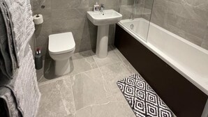 A modern bathroom with a toilet, sink, and bathtub.