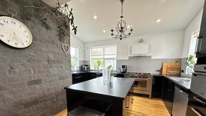 Een moderne keuken met een centraal eiland, roestvrijstalen apparatuur en een accentmuur van baksteen.