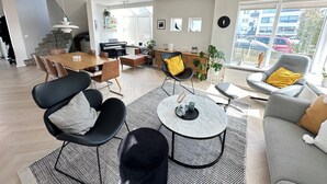 Un salon moderne comprenant un coin repas, un canapé gris, un fauteuil noir et une table basse.