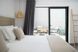 Quarto de hotel moderno com uma cama grande, varanda com mesa e cadeiras, e vista para o céu.