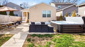 Un patio trasero con un jacuzzi, mobiliario de patio y una terraza de madera.