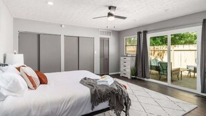 A bedroom with a bed, a ceiling fan, and a sliding glass door leading to an outdoor patio. - Suburban oasis perfect for families & groups (Columbus)