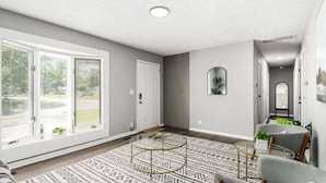 A spacious living room with a large window, a round coffee table, and a grey sofa. - Suburban oasis perfect for families & groups (Columbus)