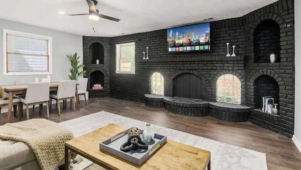 A modern living room with a fireplace, a television mounted on the wall, and a dining area with a table and chairs. - Suburban oasis perfect for families & groups (Columbus)