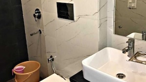 A bathroom with a white marble wall, a black countertop, a white sink, a small window, and a wooden floor.