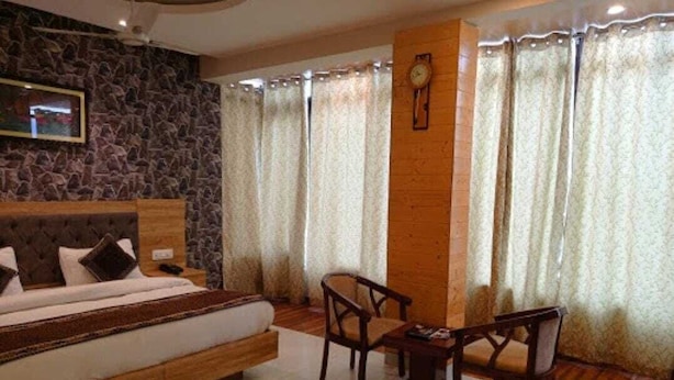 A bedroom with a bed, a wooden headboard, a stone wall, a clock, and a window with curtains.