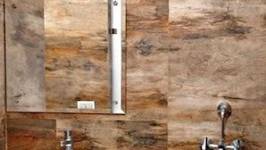 A bathroom with a sink, mirror, towel rack, and a small trash bin.