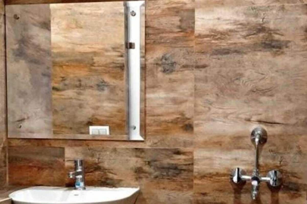 A bathroom with a sink, mirror, towel rack, and a small trash bin.