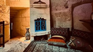 Una camera tradizionale con una parete in pietra, un tappeto decorato e un letto con cuscini a motivi.