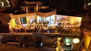Un ristorante con posti a sedere all'aperto, un cartello con la scritta 'YAMA TOUR' e diversi cartelli promozionali come 'SAFARI IN JEEP' e 'TOUR BIBLICI'.