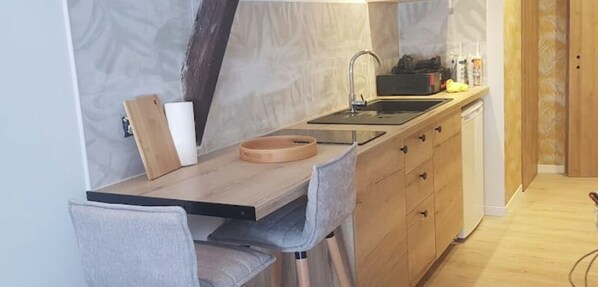 Compact kitchen with sink, dishwasher, and dining area.
