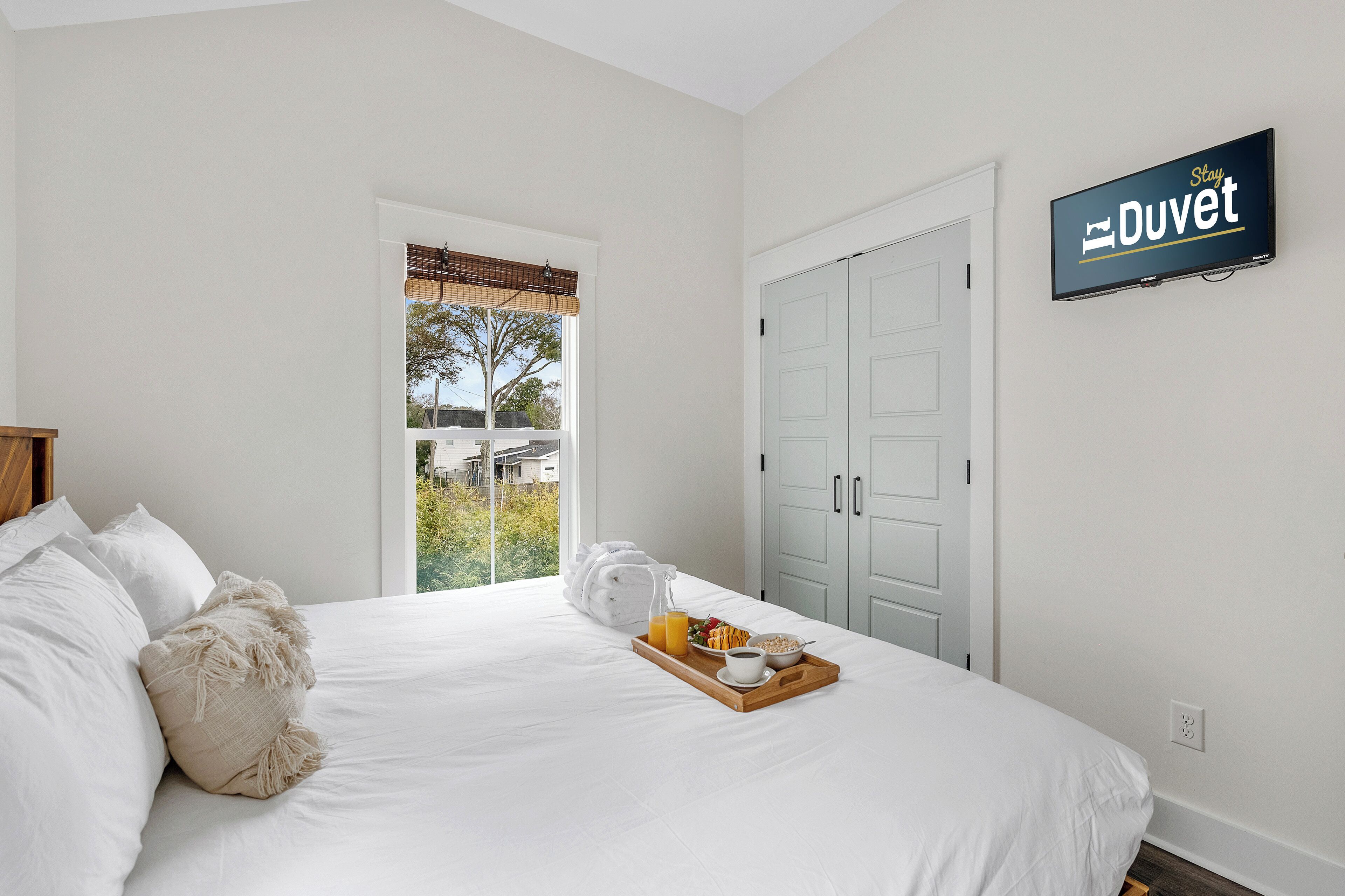 Un dormitorio con una cama, una bandeja de desayuno, un cartel que dice "Stay Duvet" y una puerta.