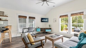 A spacious living room with a sofa, coffee table, and a TV mounted on the wall.