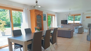 Amplia sala de estar con una mesa de comedor, sillas, un sofá y un televisor.
