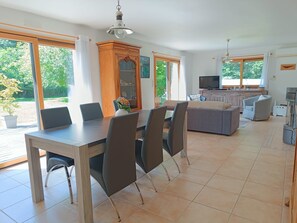 Amplia sala de estar con una mesa de comedor, sillas, un sofá y un televisor.