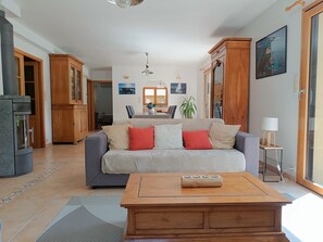 A living room with a sofa, wooden cabinet, and a coffee table. - Quiet, bright single-storey house close to beaches, port and GR34. (Moëlan-sur-Mer)