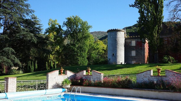 A swimming pool with a stone tower in the background. - Château Bagen (SAUVETERRE DE COMMINGES)