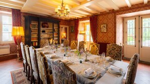 A dining room with a long table set for a meal, surrounded by ornate chairs. - Château Bagen (SAUVETERRE DE COMMINGES)