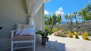 A balcony with a white bench, a potted plant, and a view of a landscape with trees and flowers. - Ornament:Infinite Nature Villa
Feel Nature, Enjoy Serenity, Live THE Experience! (Heraklion)