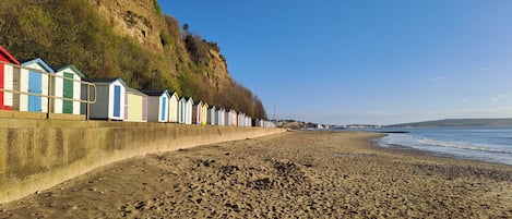 A beach with a row of colorful beach huts along the shore.