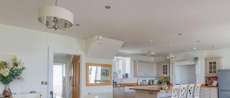 A spacious kitchen with a central island, pendant lights, and a view into the dining area.