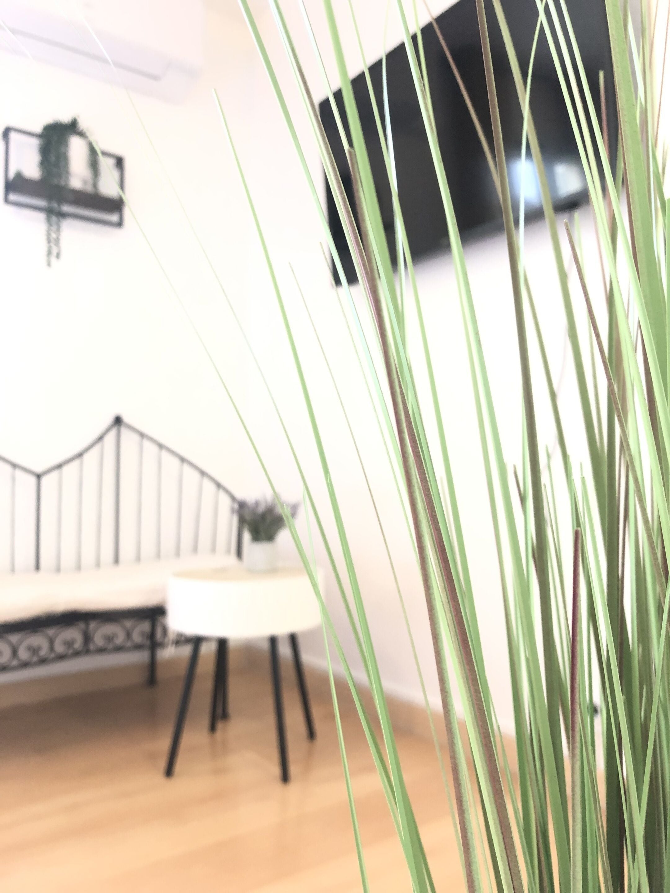 Een kamer met een houten vloer, een witte bank en een klein tafeltje.