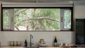 A kitchen with a window overlooking a tree.