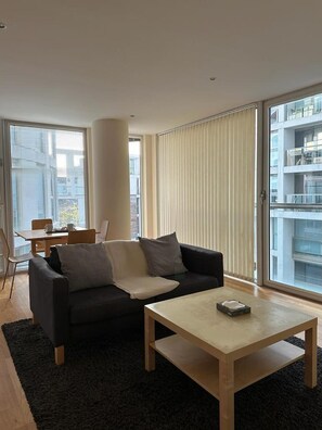 A modern living room with a sofa, coffee table, and dining area.