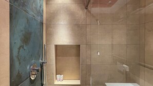 Ein modernes Badezimmer mit Dusche, Badewanne und Ablage für Pflegeprodukte.