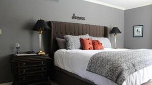 Ein Schlafzimmer mit einem großen Bett, zwei Nachttischen, einer Kommode und einer Wandlampe.
