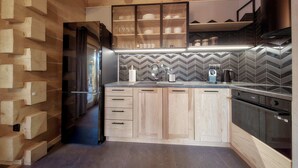 Une cuisine moderne avec des meubles en bois, un réfrigérateur noir et un dosseret de crédence en carreaux disposés en motif chevron.