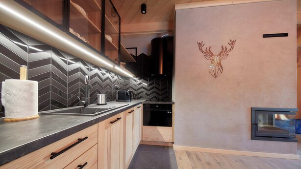 A modern kitchen with a herringbone tile backsplash, wooden cabinets, and a built-in oven.