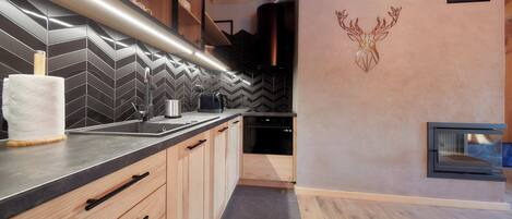 A modern kitchen with a herringbone tile backsplash, wooden cabinets, and a built-in oven.