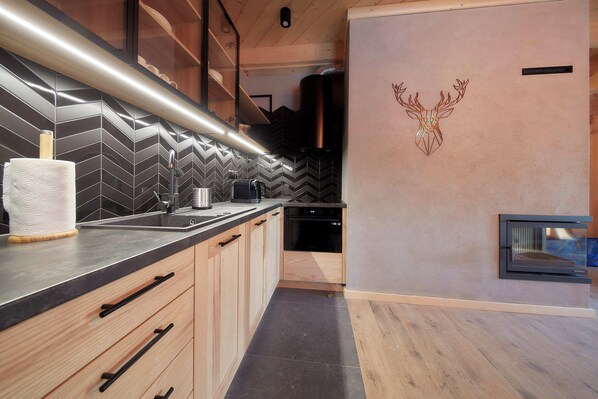 A modern kitchen with a herringbone tile backsplash, wooden cabinets, and a built-in oven. - Tatra Wood House Boutique (Zakopane)
