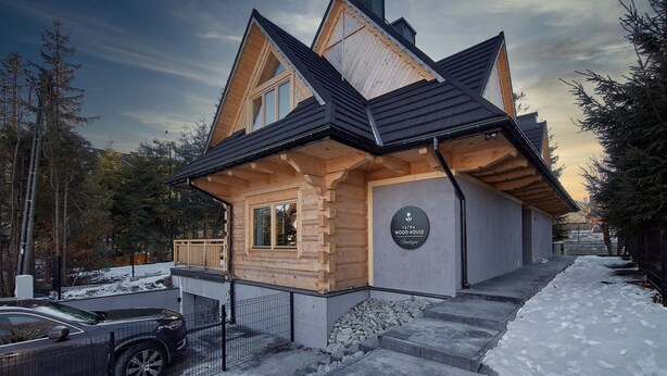 Une cabane en rondins, dotée d’un toit à forte pente, d’une façade en bois et d’une enseigne indiquant qu’il s’agit d’une « maison en bois de Tatra ».