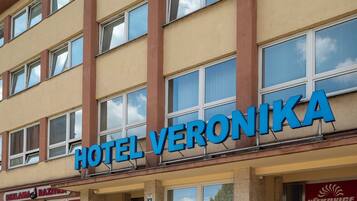 Um hotel chamado "HOTEL VERONIKA" com fachada bege, várias janelas e uma entrada visível.