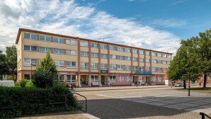 A multi-story hotel with a flat facade, multiple windows, and a paved courtyard.
