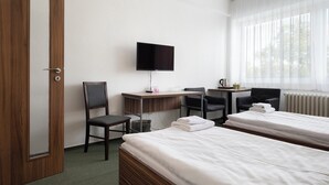 A hotel room with two beds, a desk with a TV, a chair, and a window with curtains.