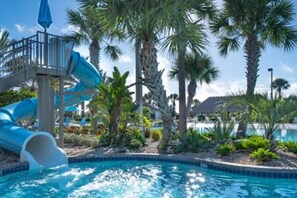 A swimming pool with a water slide, surrounded by palm trees and a clear sky. - CG 1407 Rolling Fairway Rolling Skies Poolside Cinema Spa Near Disney (Davenport)