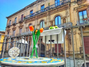A building facade with ornate architectural details, a balcony with potted plants, and a decorative metal fence. - Exclusive Stay [Duomo View + 5 Balconies] (Catania)