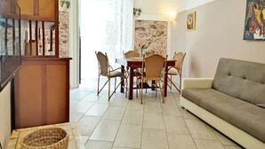 A dining area with a table and chairs, a sofa, and a staircase.