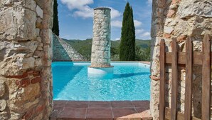 A stone pool with a central column, surrounded by stone walls and a wooden fence. - Podere Gabbiano, Castellina in Chianti, Siena and Chianti (Castellina in Chianti)