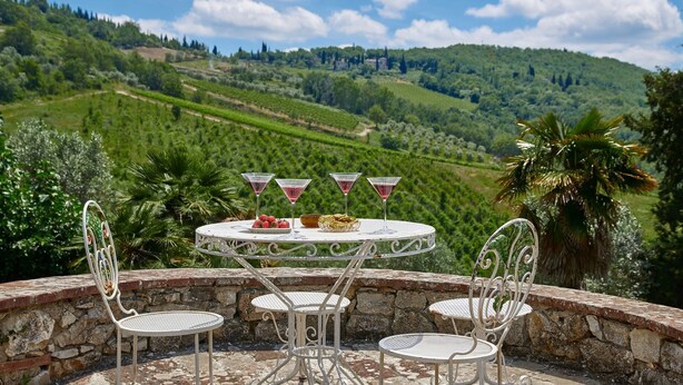 A round table with four chairs, a bottle of wine, and a bowl of strawberries and biscuits. - Podere Gabbiano, Castellina in Chianti, Siena and Chianti (Castellina in Chianti)