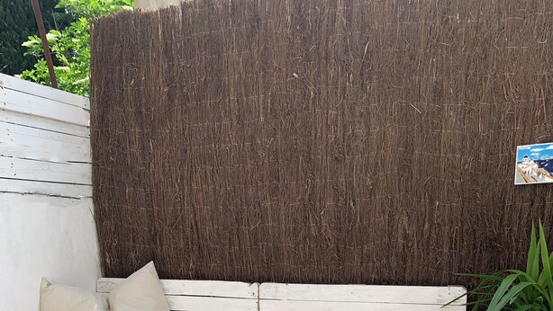 A corner seating area with a white sofa, green cushions, and a small table with a white vase and cups.