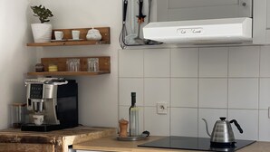 A kitchen with a coffee machine, oven, and various utensils on the counter.