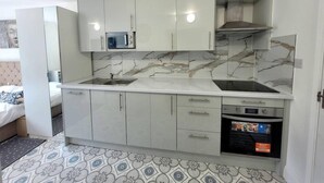 Una cocina compacta con armarios blancos, microondas, estufa y horno.